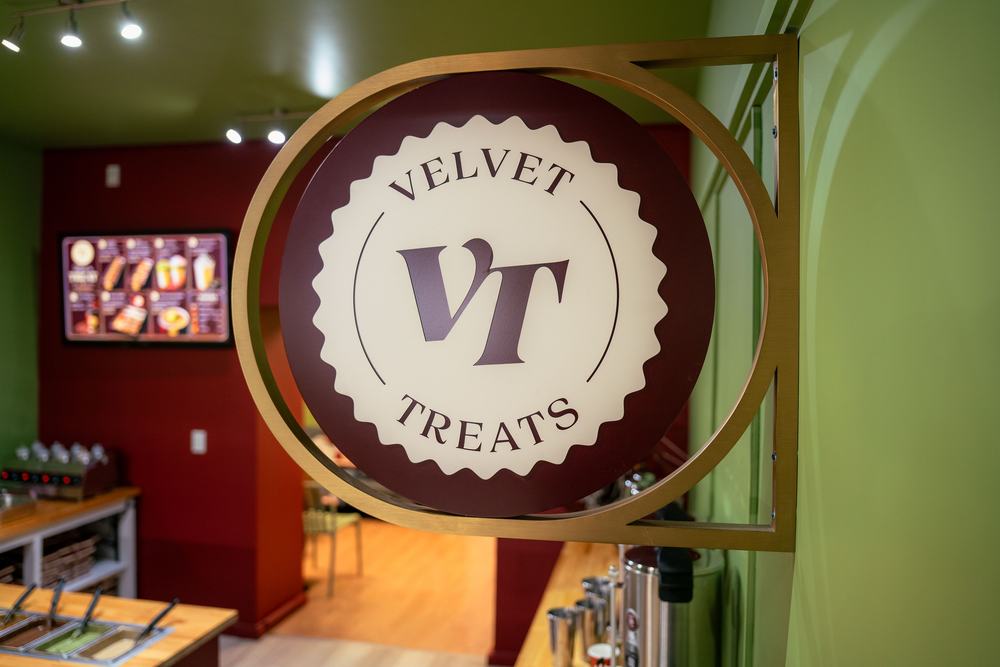 The Velvet Treats seal on its gold hanging sign