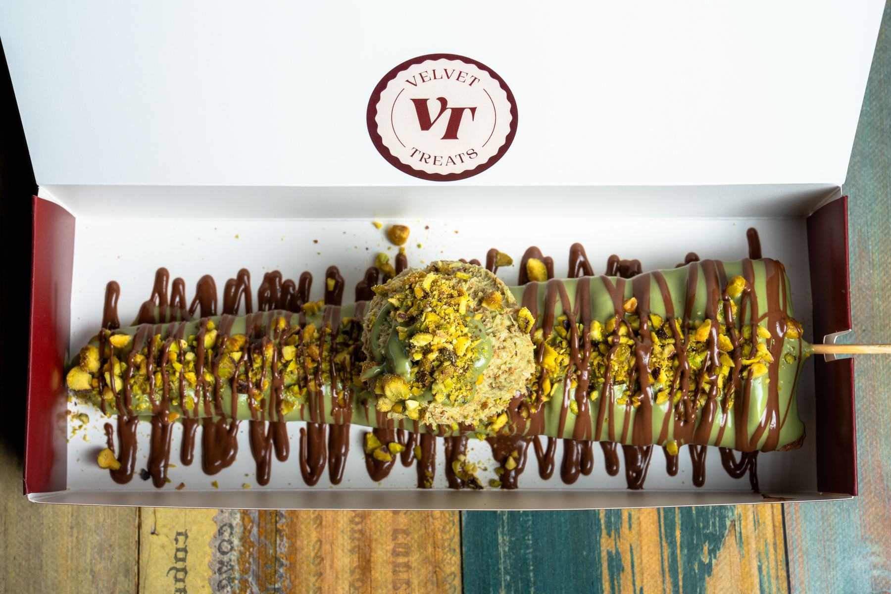 A Velvet Wand dipped in matcha white chocolate, topped with pistachio kunafa and finished with chocolate drizzle